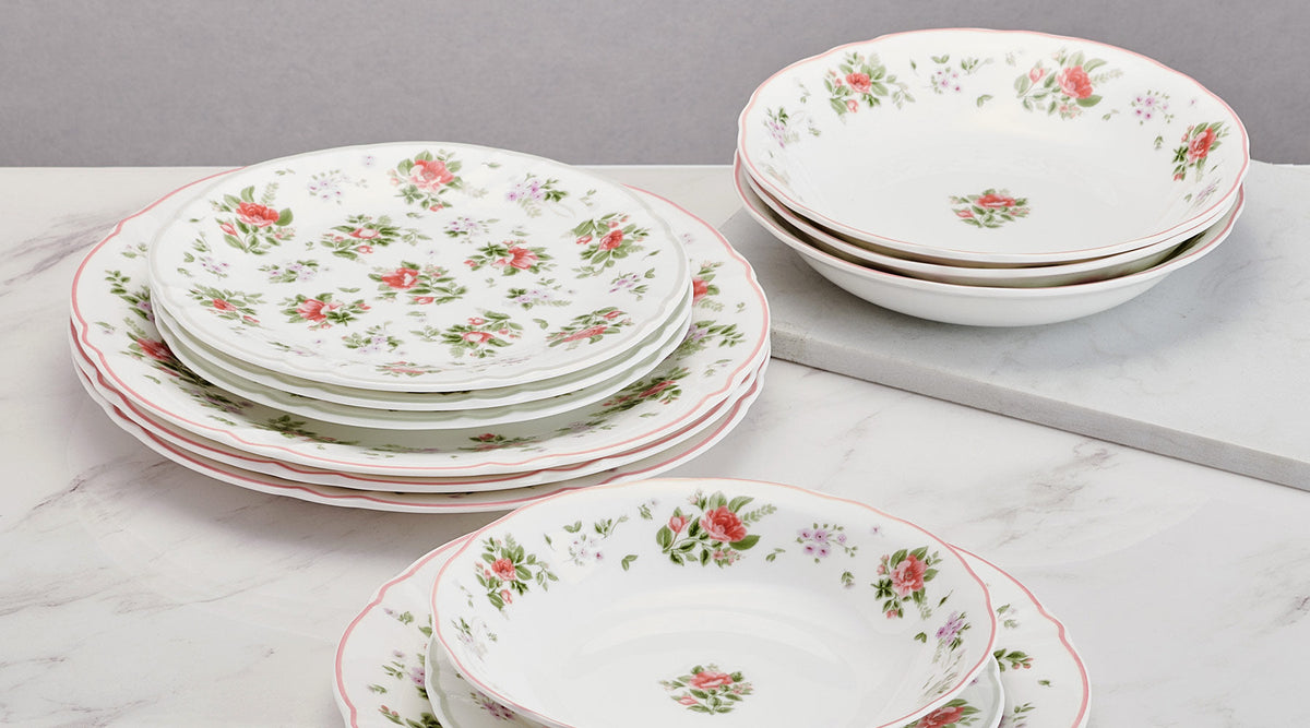 Stacks of white floral china plates with pink scalloped rims and rose bouquets from the Darling collection.