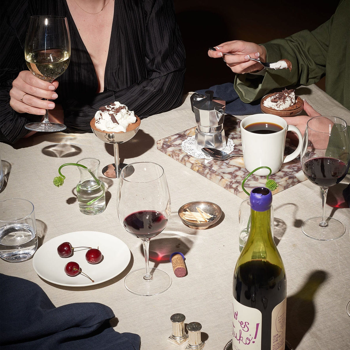 Dune Beige linen tablecloth in an intimate dinner scene with wine glass dessert bowls and a coffee mug