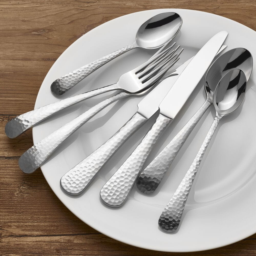 Close-up of hammered Opulent flatware pieces laid across a white plate.