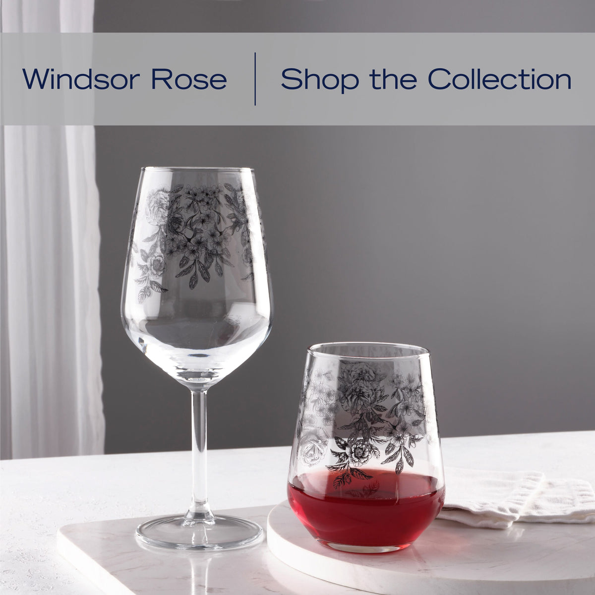 Stemless Windsor Rose glass with black floral motif filled with red wine on a white marble surface