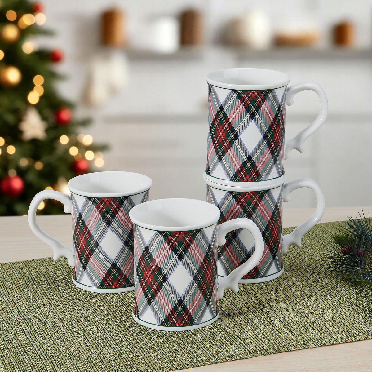 Front mug from the Tartan White set on a woven mat with a Christmas tree in the blurred background.