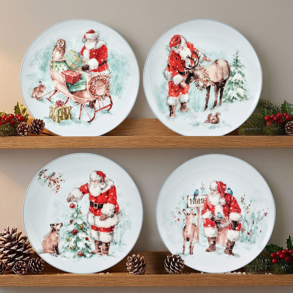 Two festive salad plates featuring Santa scenes one with a sleigh and gifts the other with Santa beside a reindeer in the snow