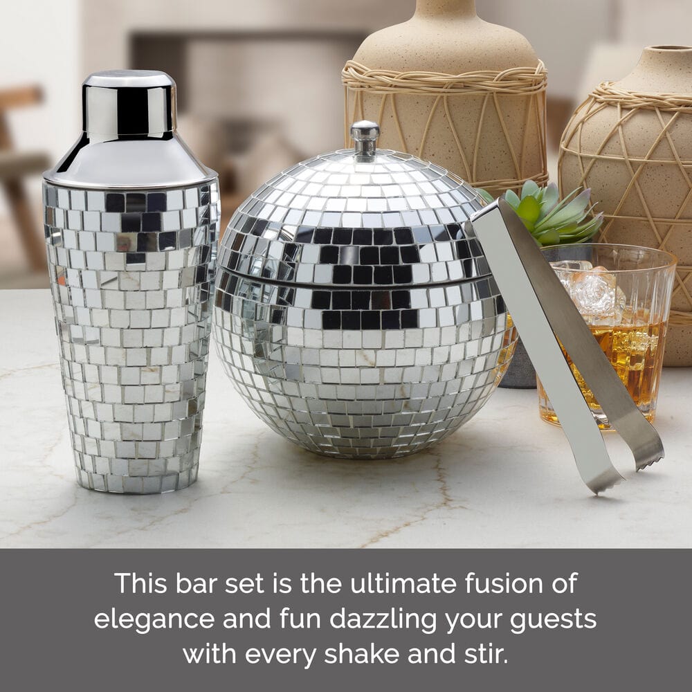 Shiny disco ball mosaic shaker and round ice bucket on a marble counter with tongs nearby