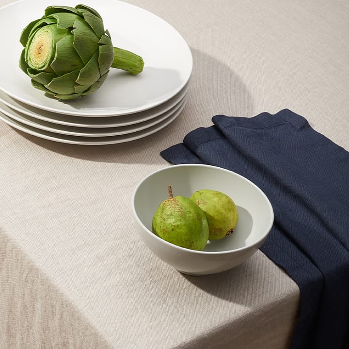 Dune Beige European Linen tablecloth setting with stacked white plates artichoke bowl of pears and a navy napkin