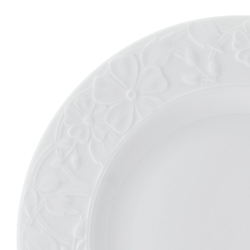 Close up of a white dinner plate edge with embossed floral rim from the Claire set.
