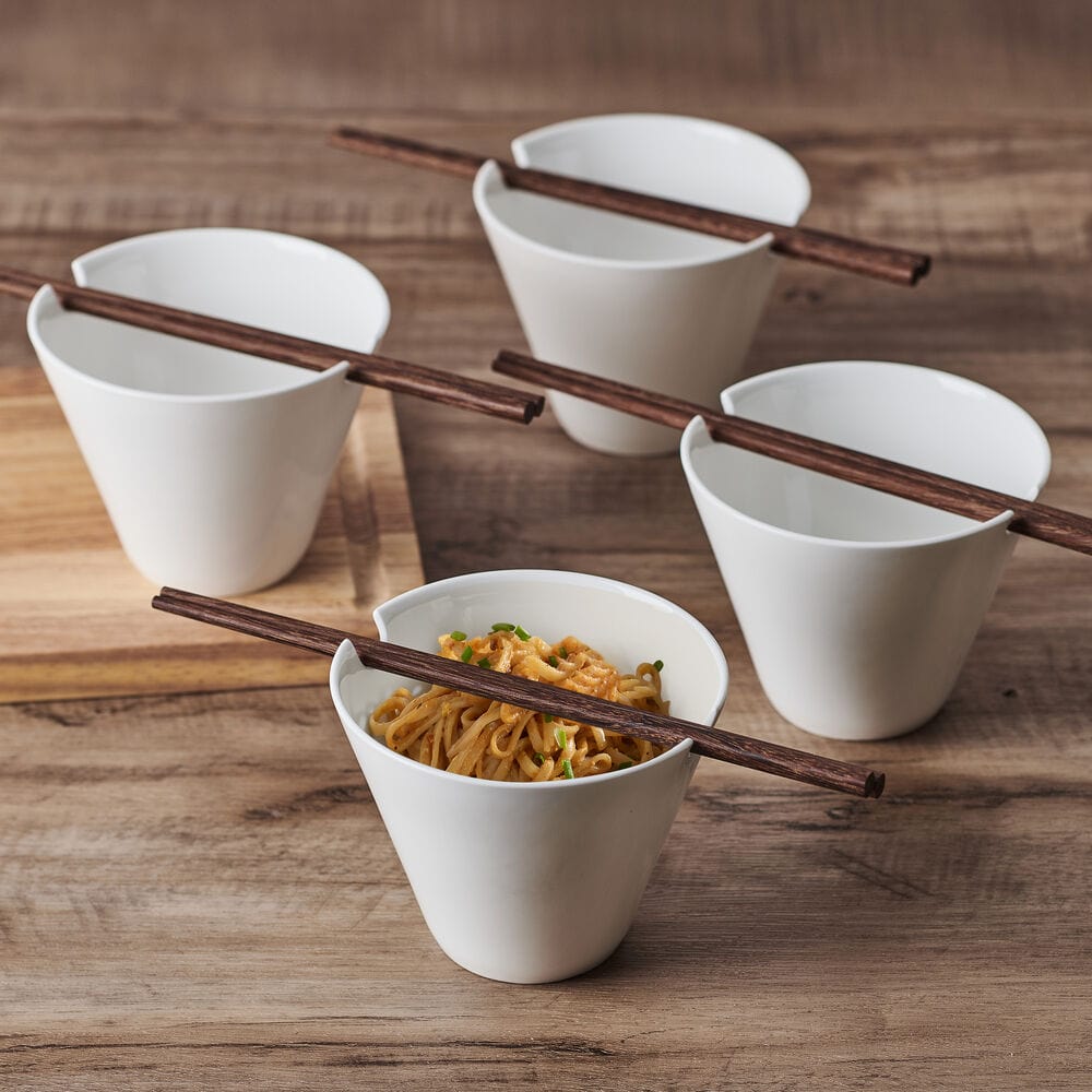 Delray set of four white noodle bowls with chopsticks arranged on a wooden surface, one bowl filled with noodles.
