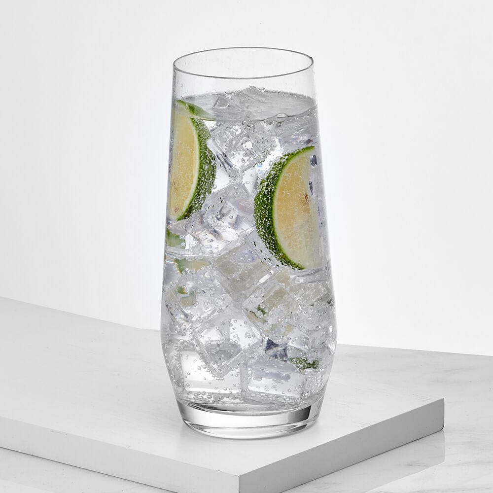 Tall clear highball glass filled with ice and lime wedges.