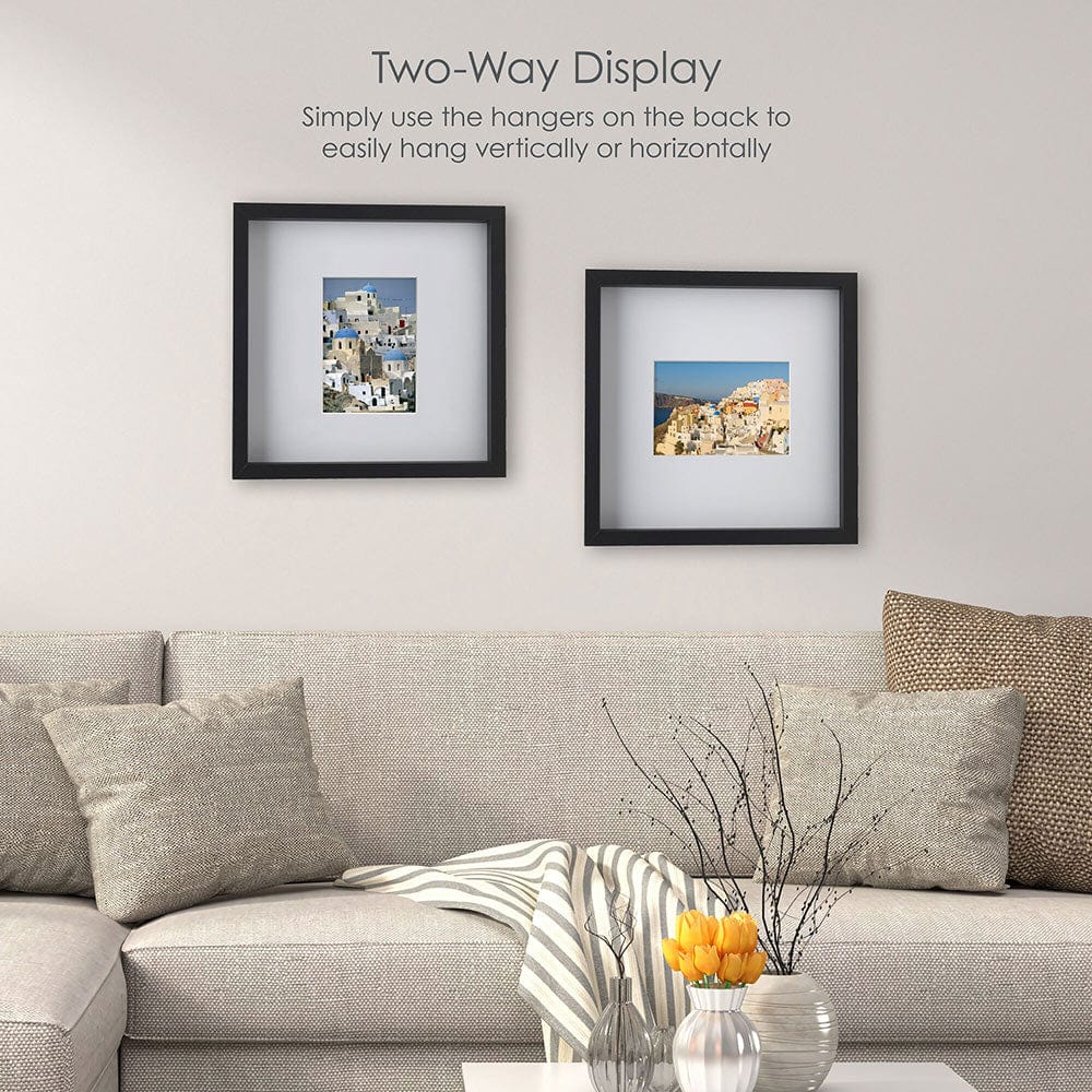 Living room scene with two black gallery frames mounted above a sofa, each frame containing a small landscape photo