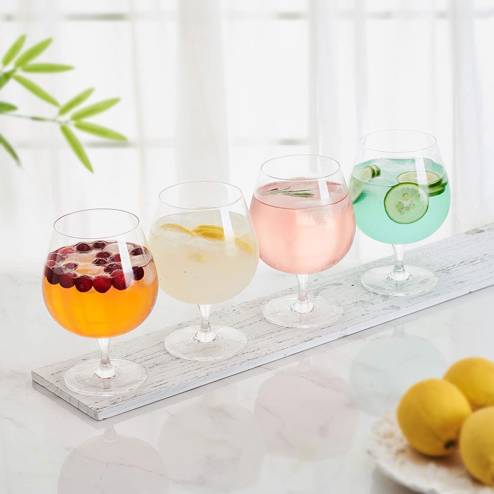 Set of four balloon glasses with colorful drinks on a white wooden tray