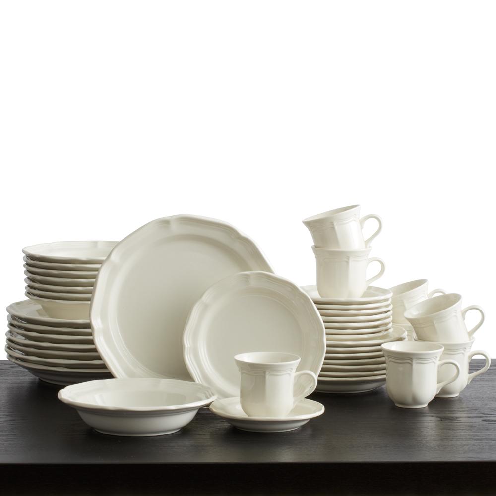Arrangement of white French Countryside dinnerware on a dark table with stacked plates bowls and mugs