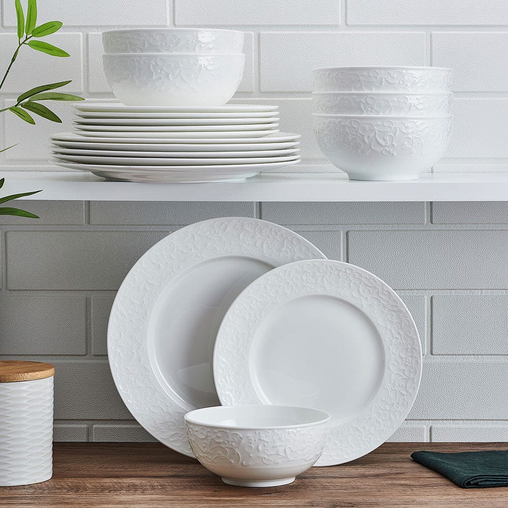 Parchment White embossed dinnerware set bowls and plates stacked on a shelf.