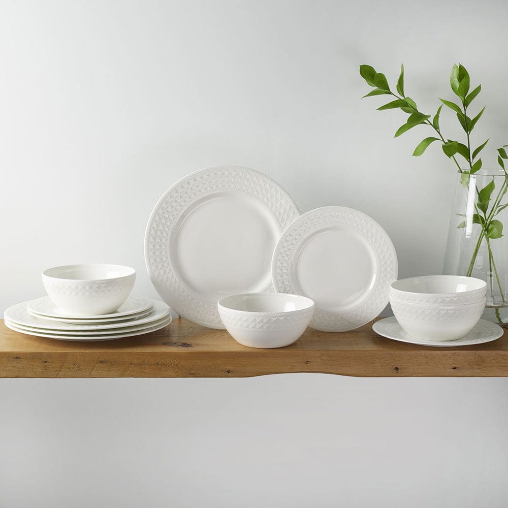 Patterson Vegan Bone 12 piece dinnerware set for four displayed on a wooden shelf with bowls and plates.