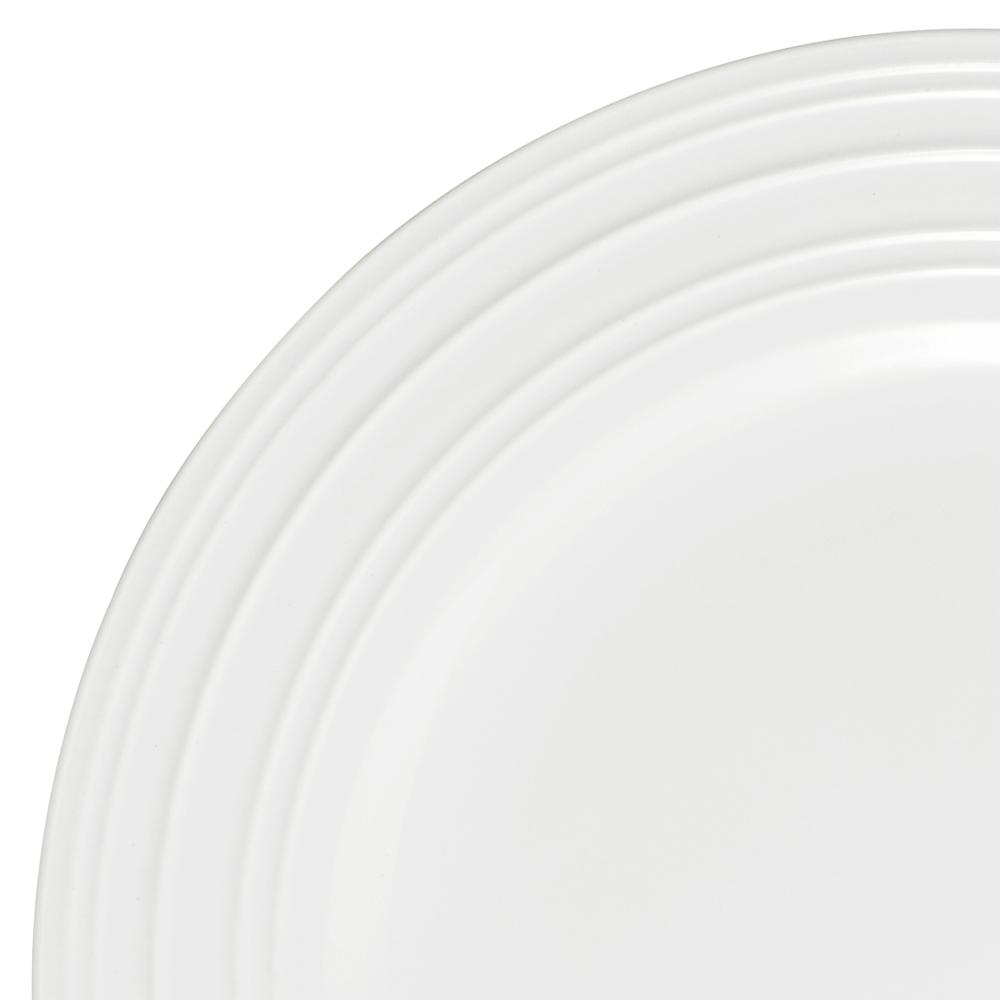 Close up of a white ceramic dinner plate with concentric ridges from the Swirl Bone collection