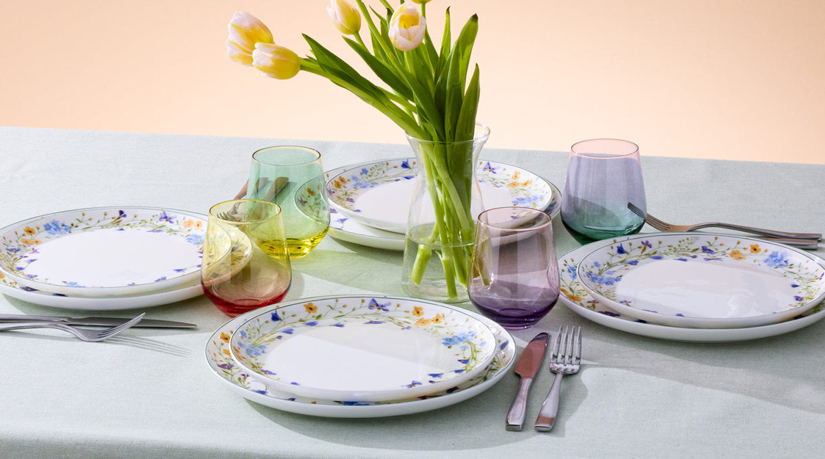 Quinn collection table setting with floral rimmed plates, tinted glassware, and a tulip centerpiece.