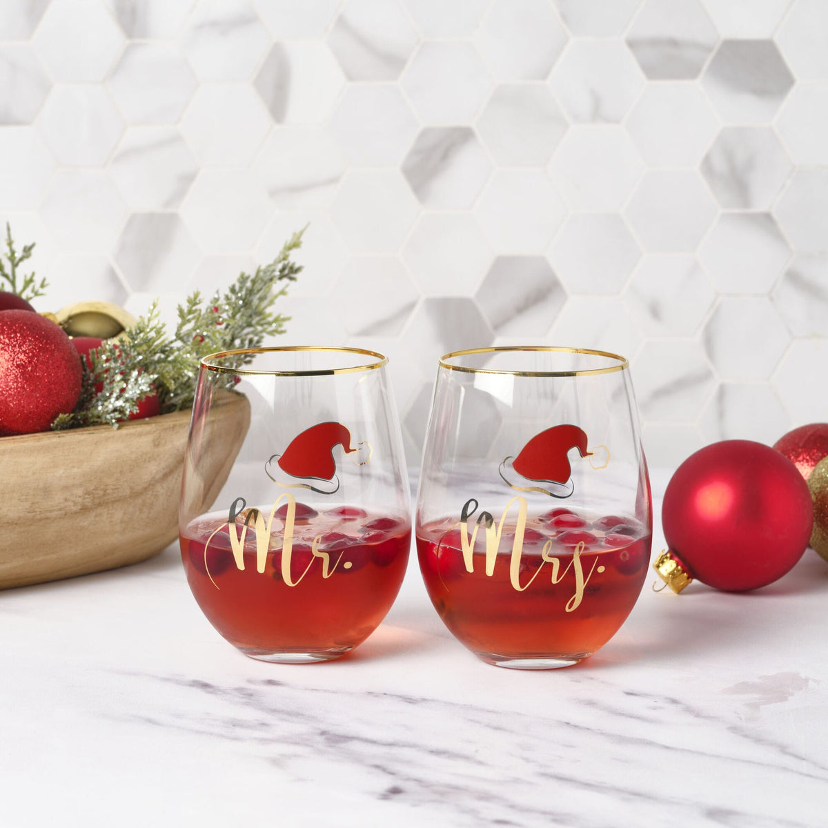 Pair of stemless wine glasses with gold rims featuring Mr and Mrs Santa graphics on festive display
