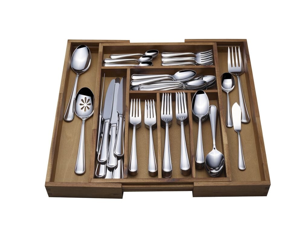 Open wooden drawer organizer filled with a full flatware set neatly arranged by type