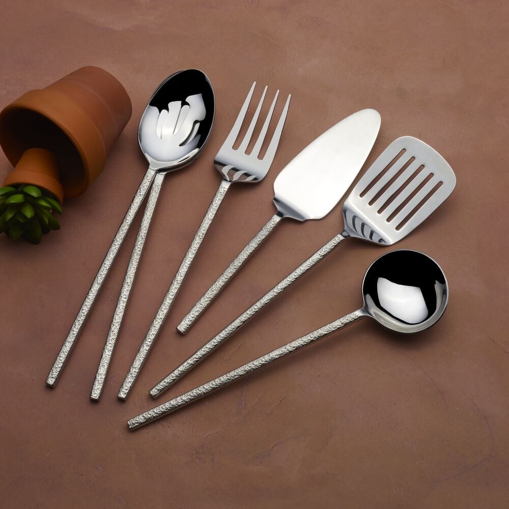 Paragon forged six piece serving set with hammered handles laid out on a brown surface