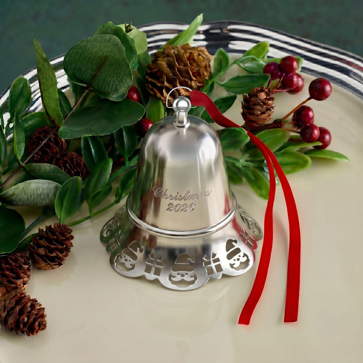 Silver bell ornament nestled among greenery, pinecones, and red ribbons in a Christmas centerpiece