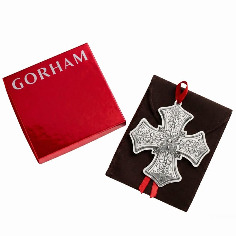 Gorham red gift box beside a silver cross ornament resting on a dark brown pouch