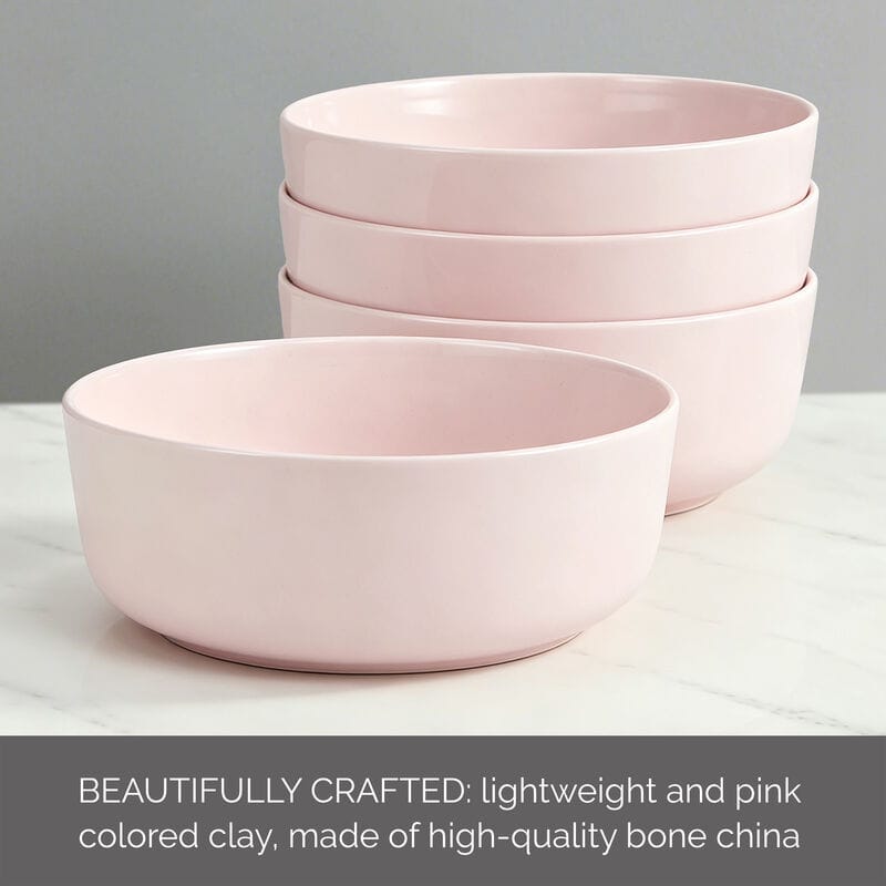 Stack of pale pink bowls on a light surface with a muted gray background.