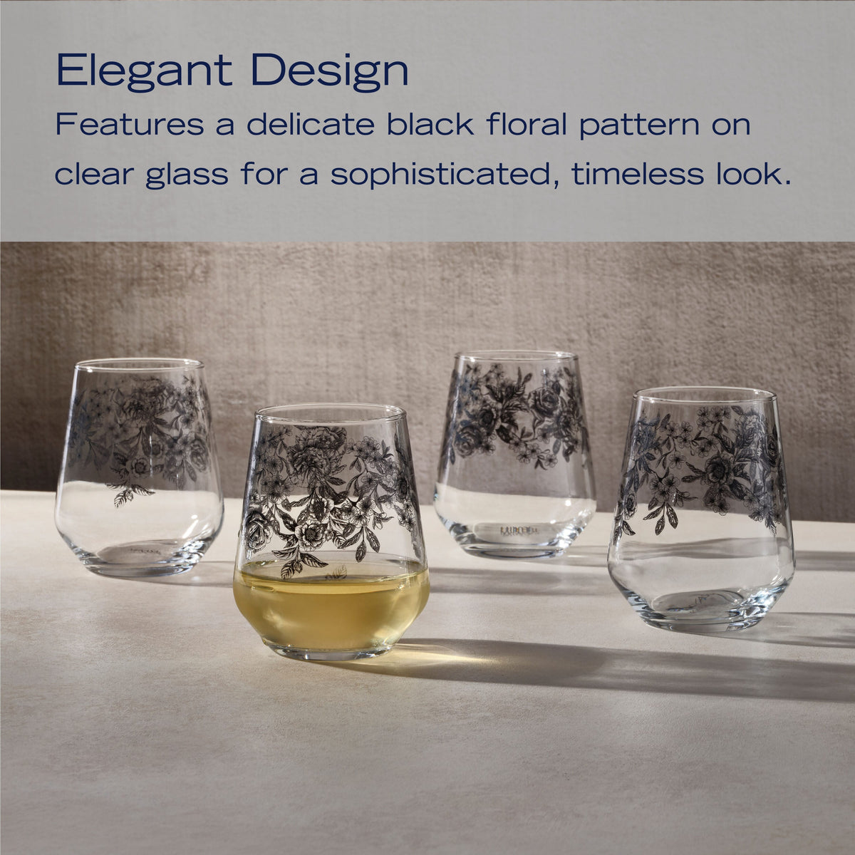 Four stemless wine glasses with a black floral pattern on clear glass displayed on a light surface
