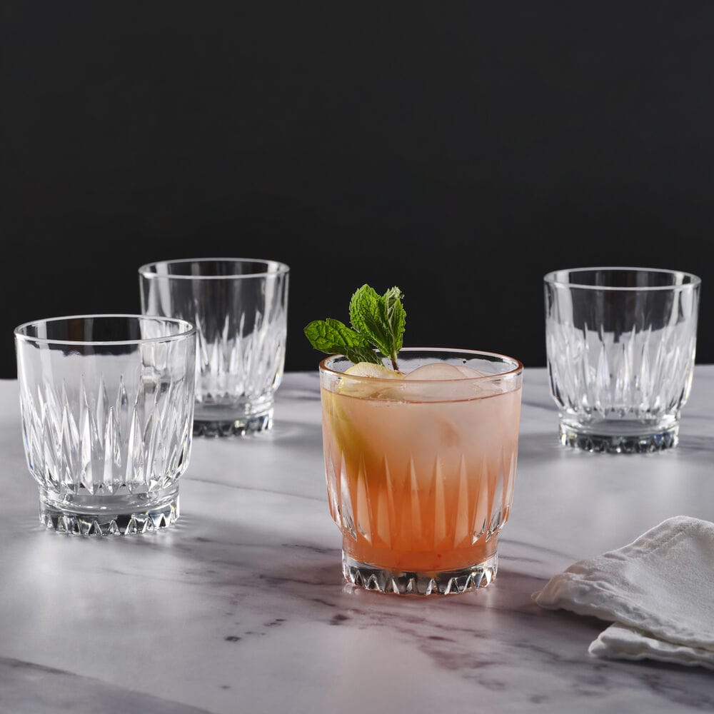 Four Hampshire crystal double old fashioned glasses surround a pink cocktail with mint on a marble surface
