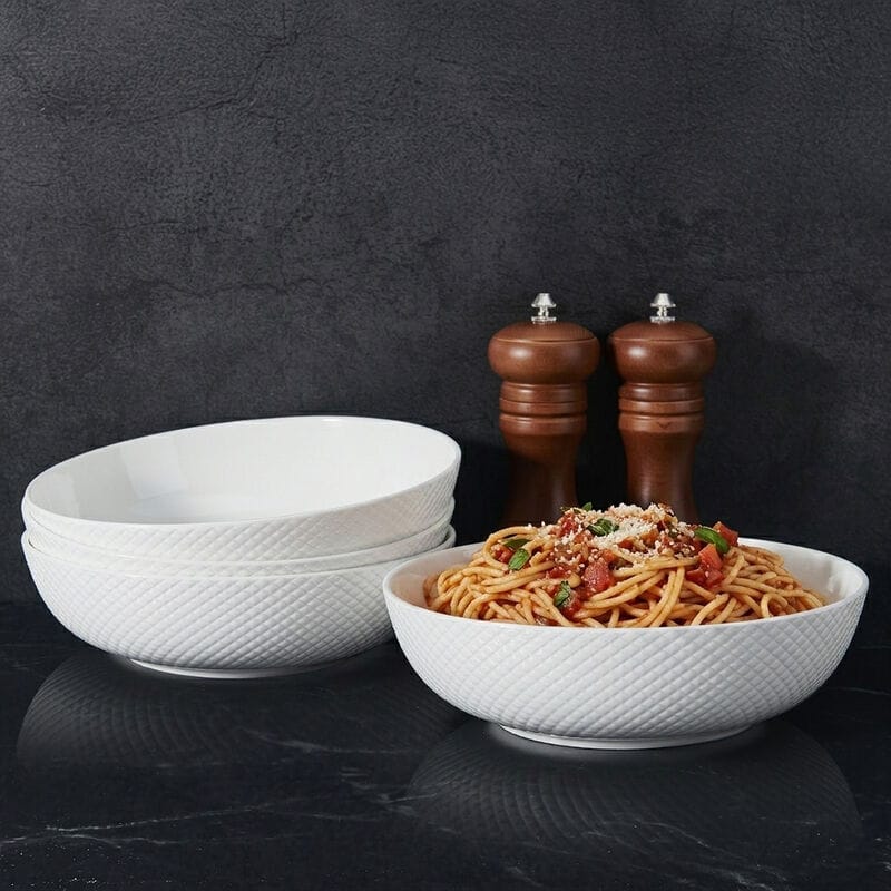 Huntington white textured pasta bowl filled with spaghetti with stacked bowls and pepper mills in the background