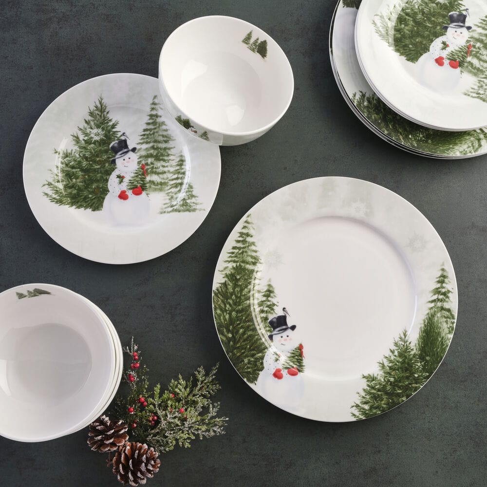 Overhead view of Snowman's Winter 12 Piece Dinnerware Set for four showing plates and bowls with snowman and evergreen forest designs.