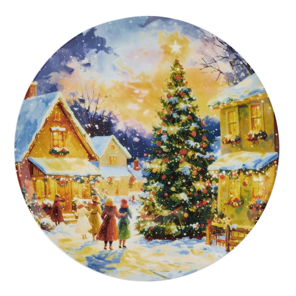 Snowy village at dusk with a tall decorated Christmas tree and warmly lit cottages