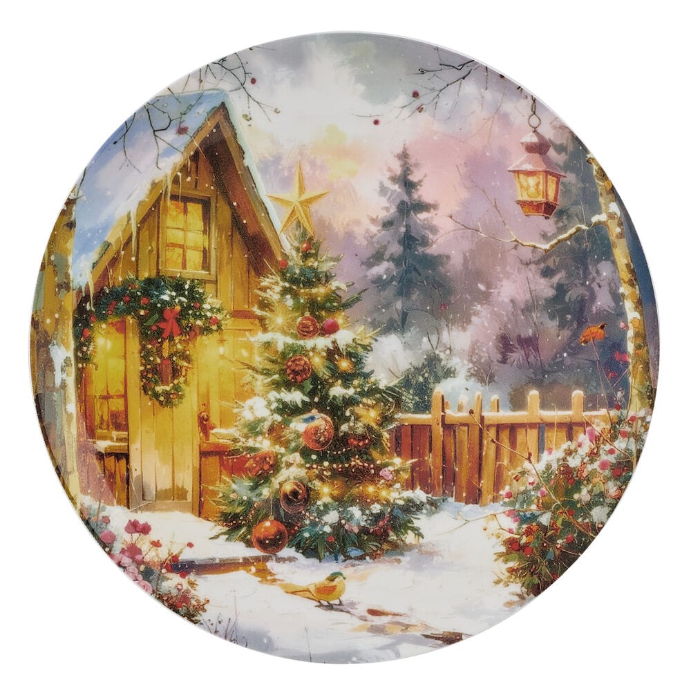 Round Christmas plate with a snow covered yard, decorated evergreen tree, and a wooden fence in a winter scene