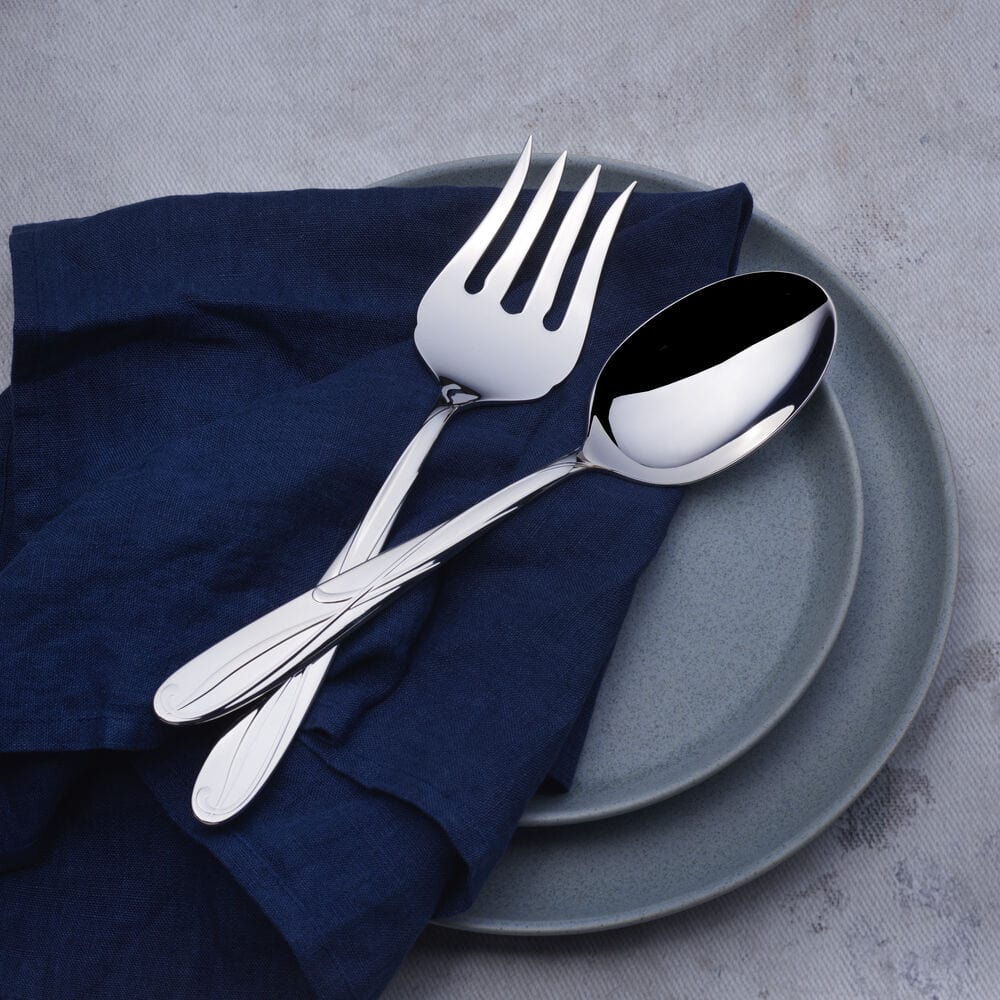 Cocoa Blossom serving fork and spoon resting on a navy napkin atop gray ceramic plates