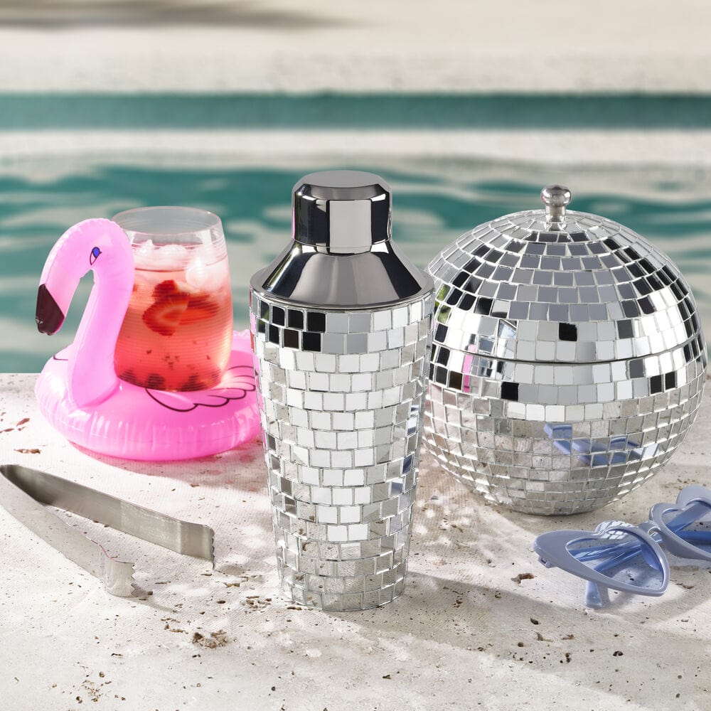 Poolside scene with a pink flamingo pool float and the disco ball ice bucket and shaker beside a drink