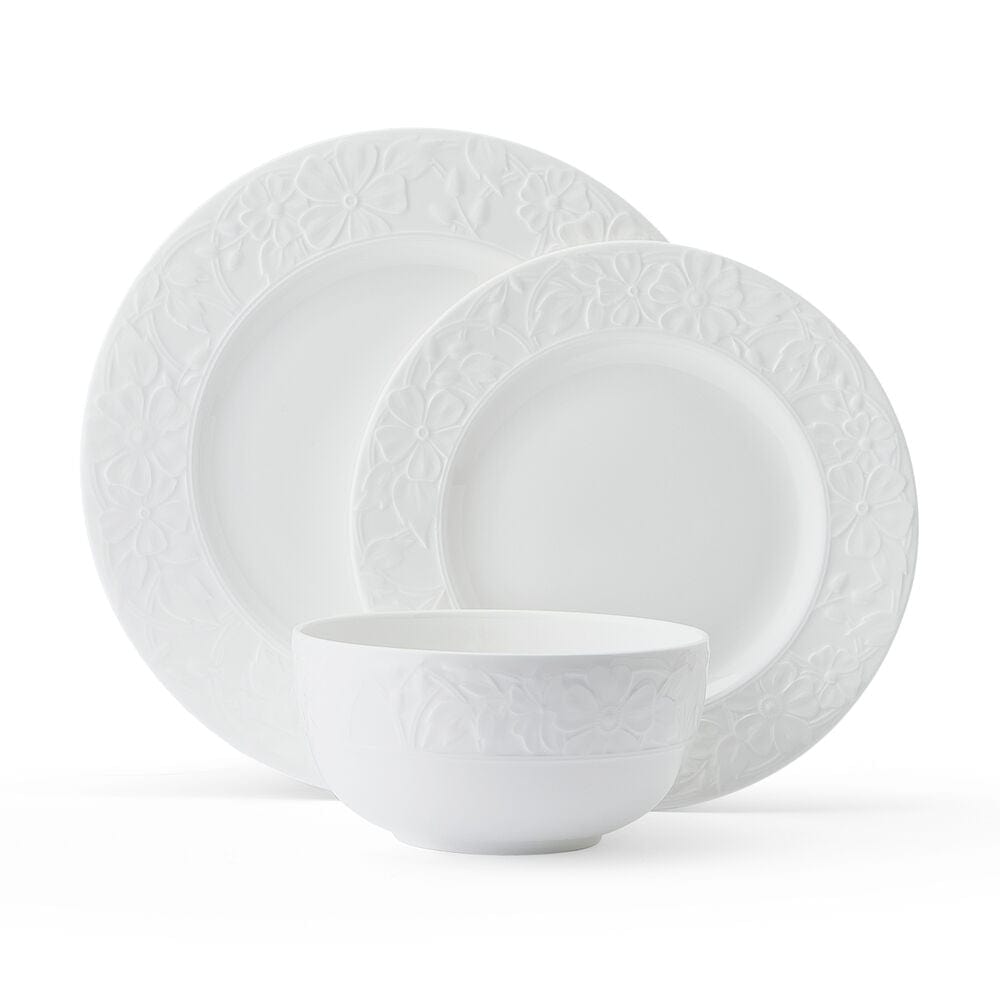 White bowl with embossed floral border paired with matching plates from the Claire 12 Piece Dinnerware Set