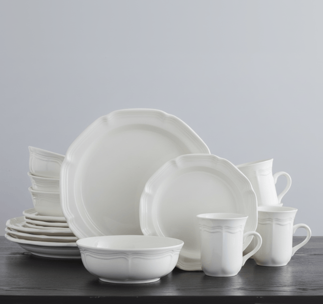 French Countryside white dinnerware set for four with plates bowls and mugs displayed on a dark tabletop