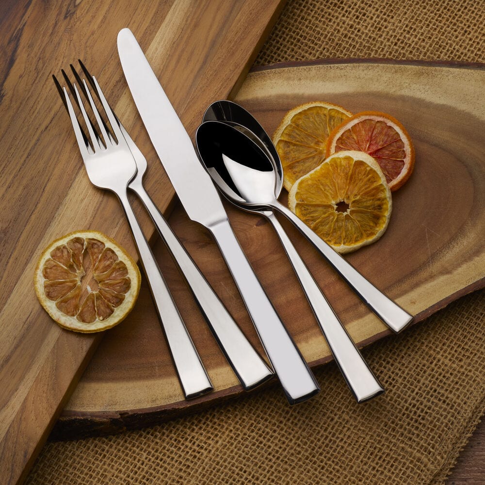Essex flatware for eight laid out on a wooden board with sliced citrus fruit garnish