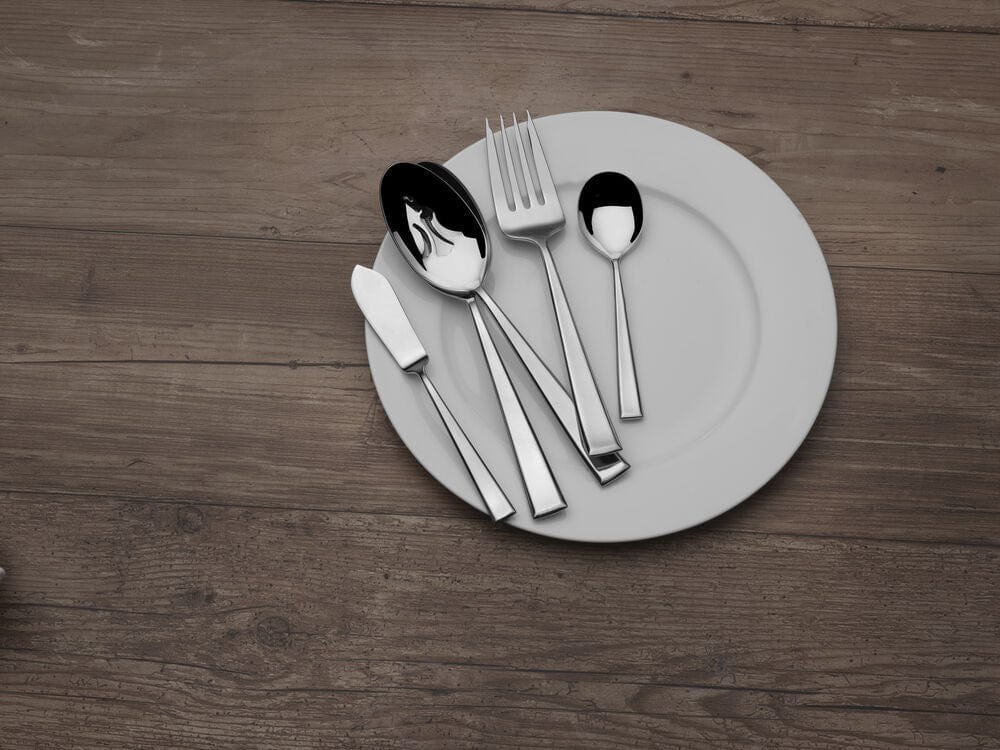 Essex 45 piece flatware set arranged on a round plate placed on a wooden table