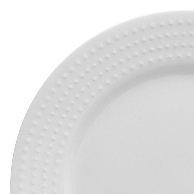 Close up of a white plate with a raised dotted rim against a light background