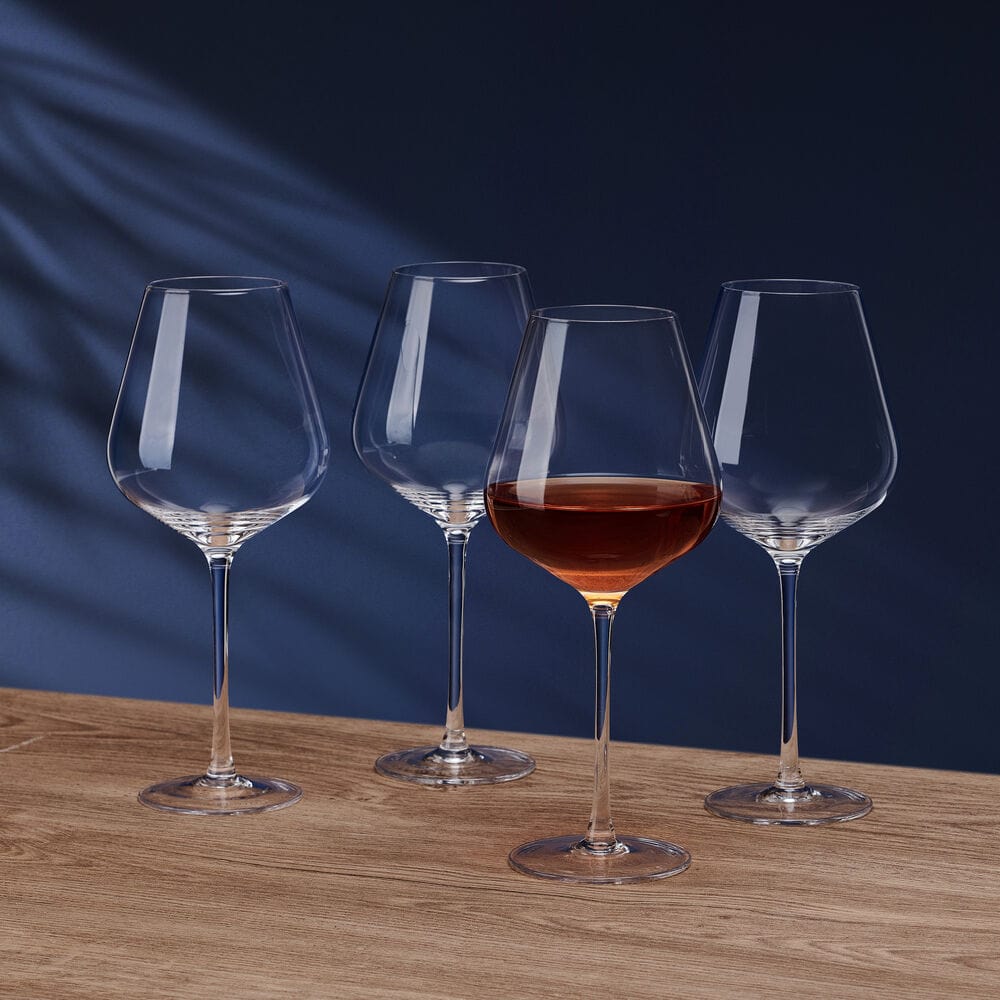 Samantha set of four red wine glasses arranged on a wooden tabletop against a dark blue background.