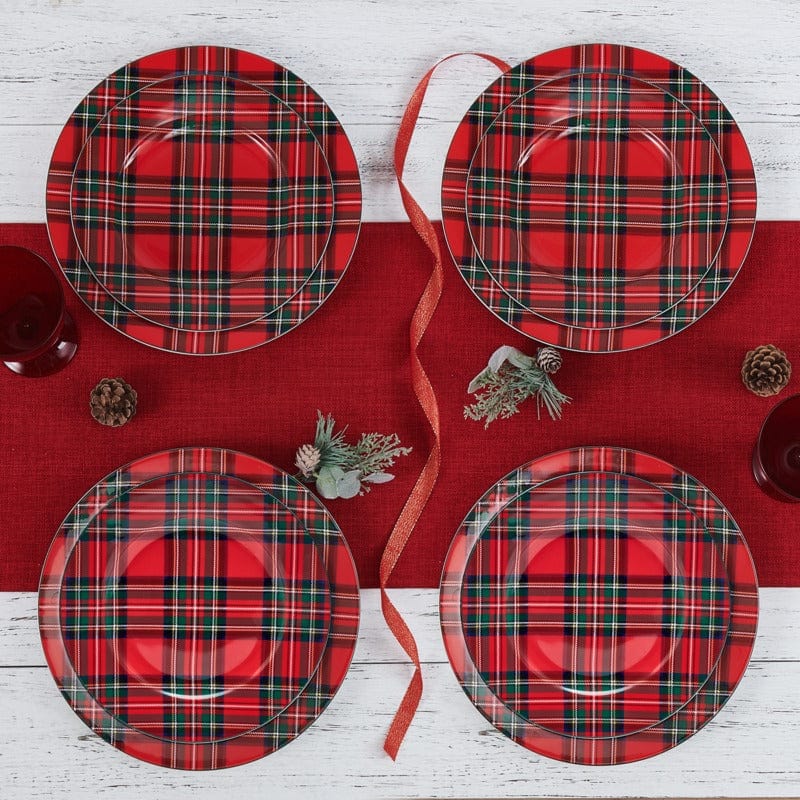 Set of four red tartan plaid salad plates arranged on a red table runner with ribbon and pinecone accents