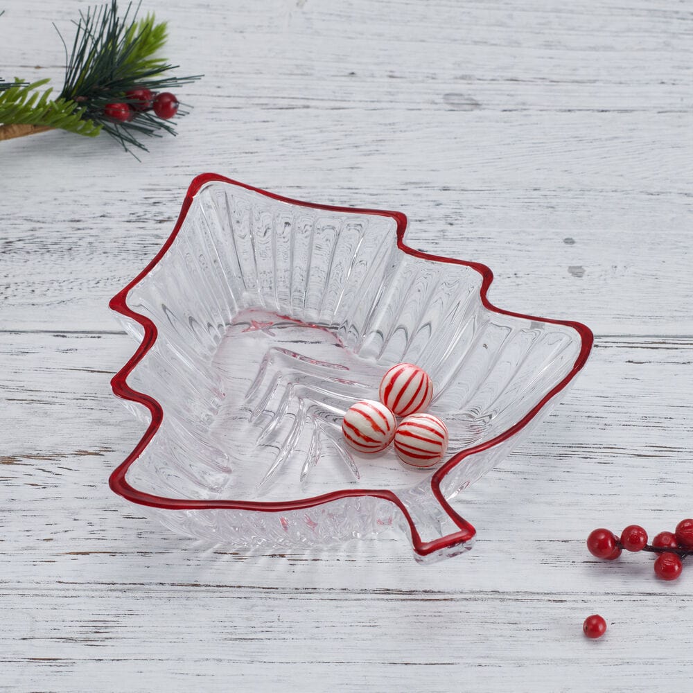 Leaf shaped clear glass candy dish with a red rim holding three striped red and white candies