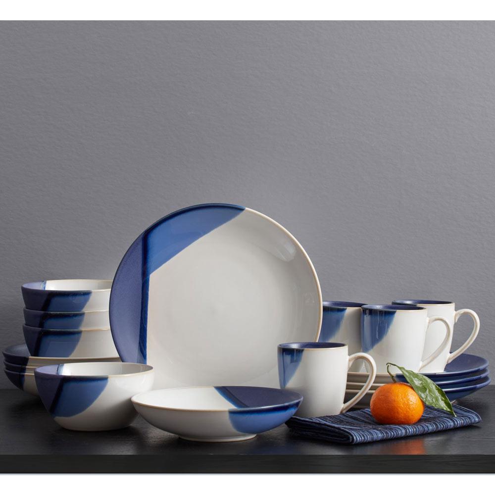 Caden blue and white dinnerware set for four with plates bowls and mugs arranged on a dark surface