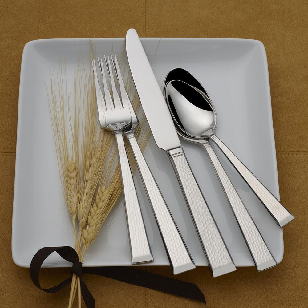 Kyler 20 piece flatware set arranged on a white plate beside decorative wheat stems tied with a ribbon