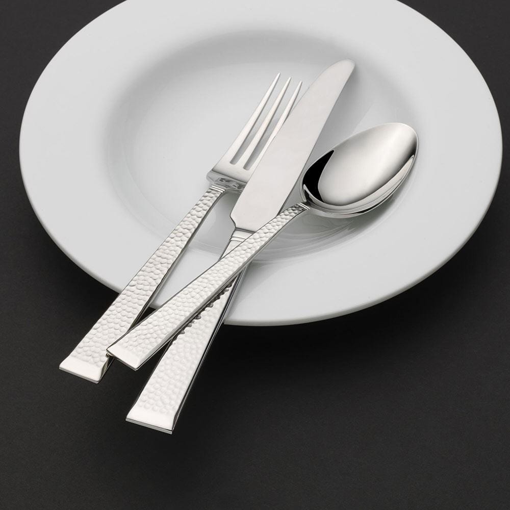 Kyler flatware set with knife fork and spoon spread over a white plate on a dark background