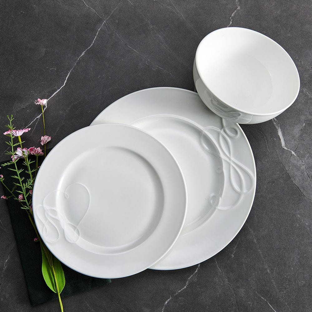 White Love Story 18 piece dinnerware set for six arranged on a dark surface with plates bowls and pink florals